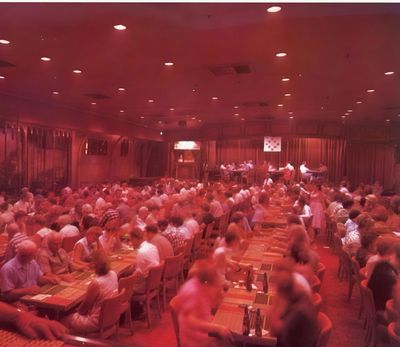 A restored 1954 brochure photograph of the Showboat bingo hall filled with players, the lit flashboard on the far wall