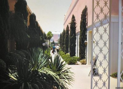 A landscaped walkway with lawns and young trees leading past the Showboat's low white hotel wings in 1968